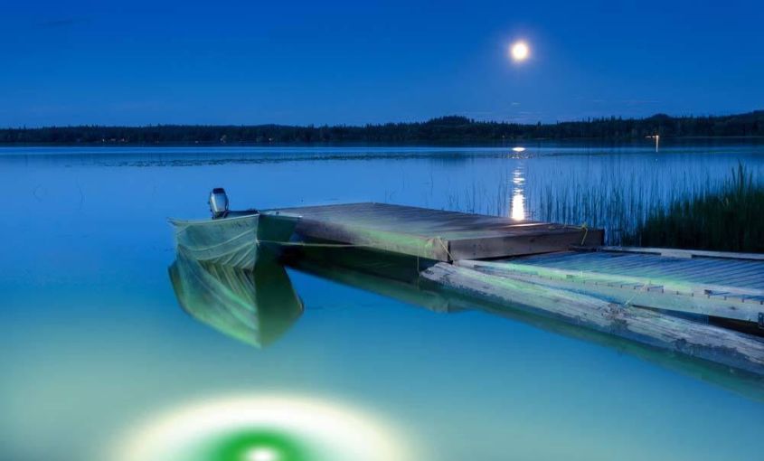 Green underwater LED lights illuminating a residential dock.