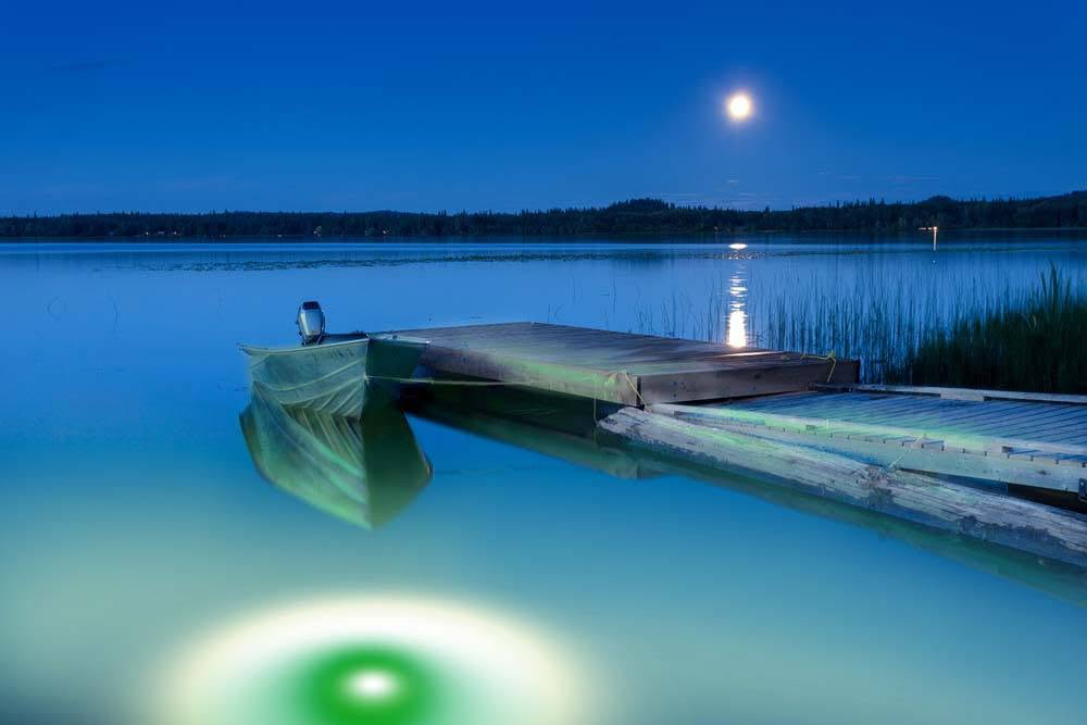 Green underwater LED lights illuminating a residential dock.