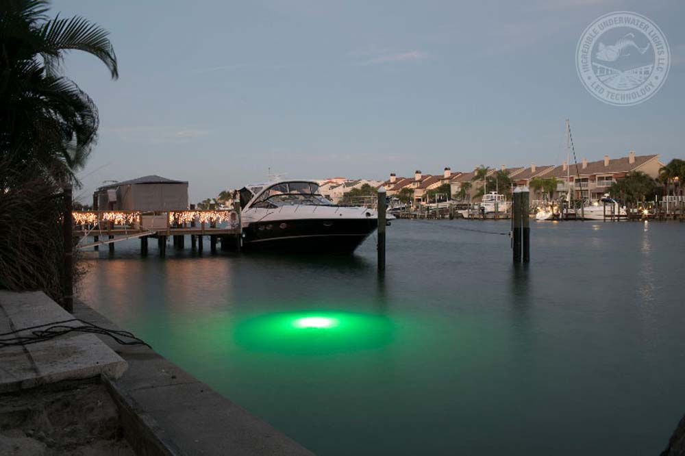 A green underwater lighting next to a ship. 