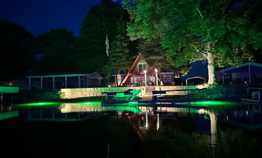 Green underwater LED lights beneath a waterfront dock.