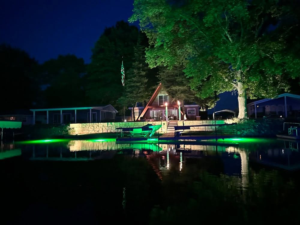 Green underwater LED lights beneath a waterfront dock.