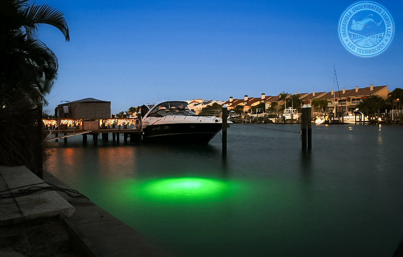 A ship parked in the water with green underwater lights.