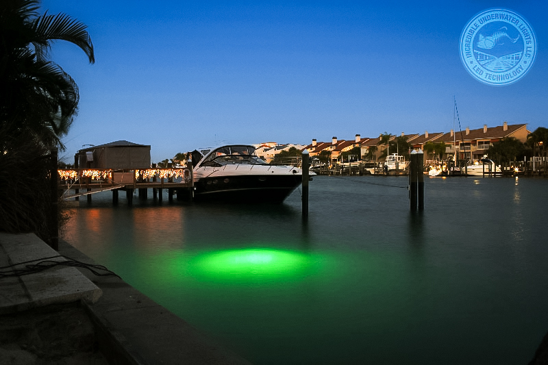 A ship parked in the water with green underwater lights.