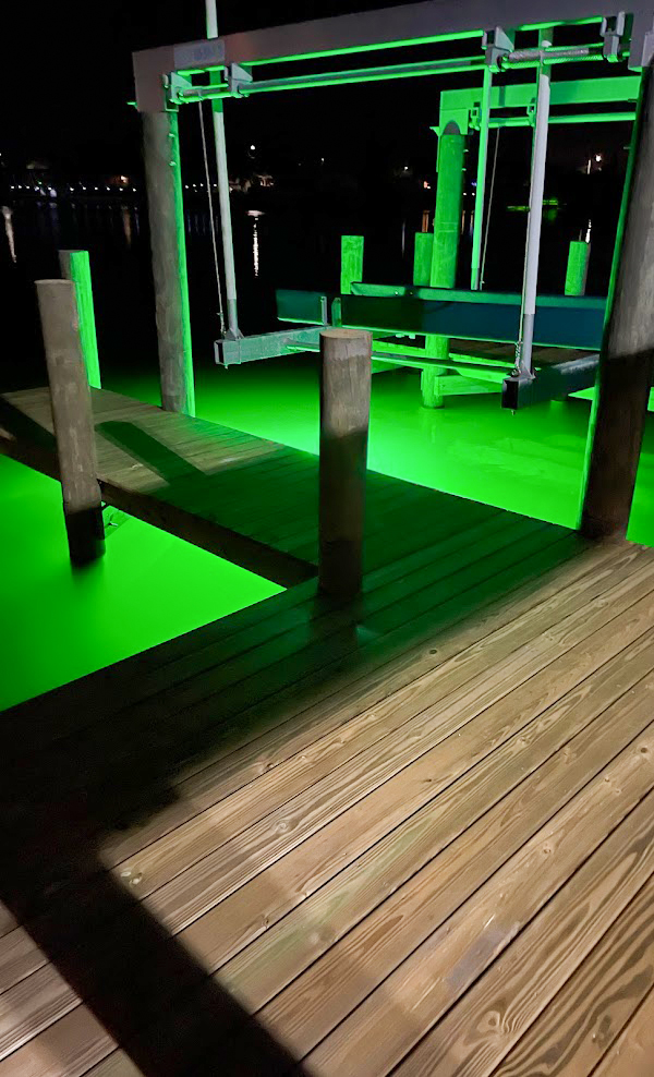 Green underwater lights installed near a wooden dock.