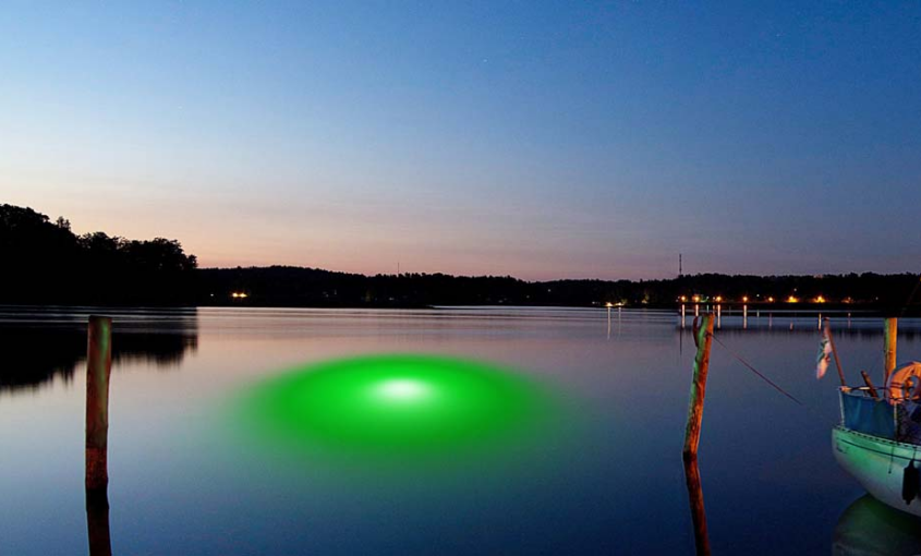 An underwater LED light illuminating the water near a dock