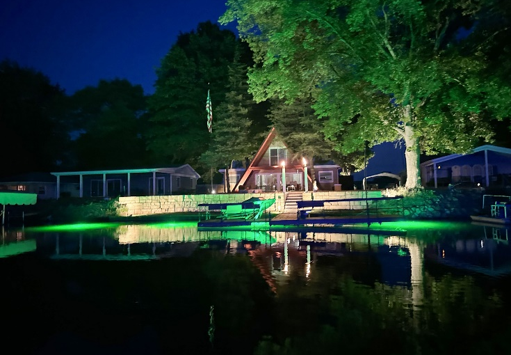A well-lit dock with LED underwater lights at night.
