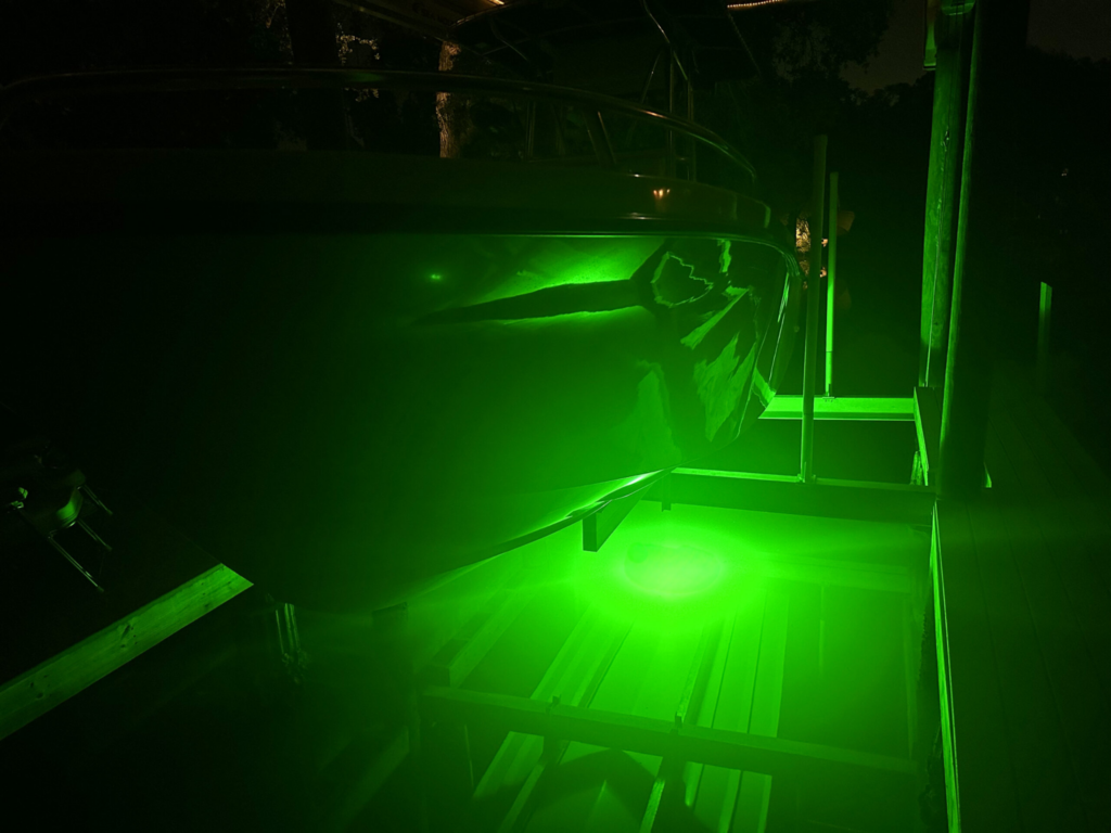 A green fishing light illuminating the bottom of a boat