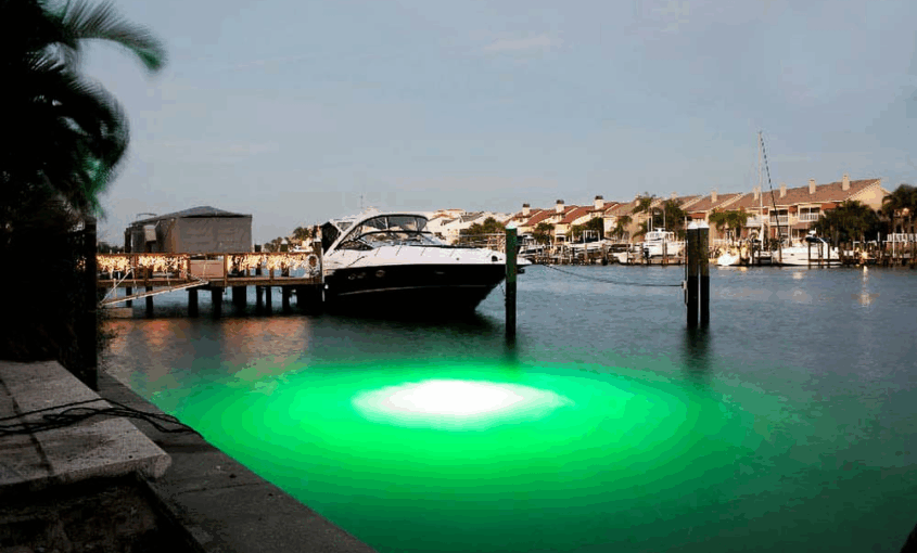 A green colored underwater LED light next to a dock area.