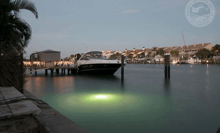 A boat parked near the dock with a green colored LED Light.