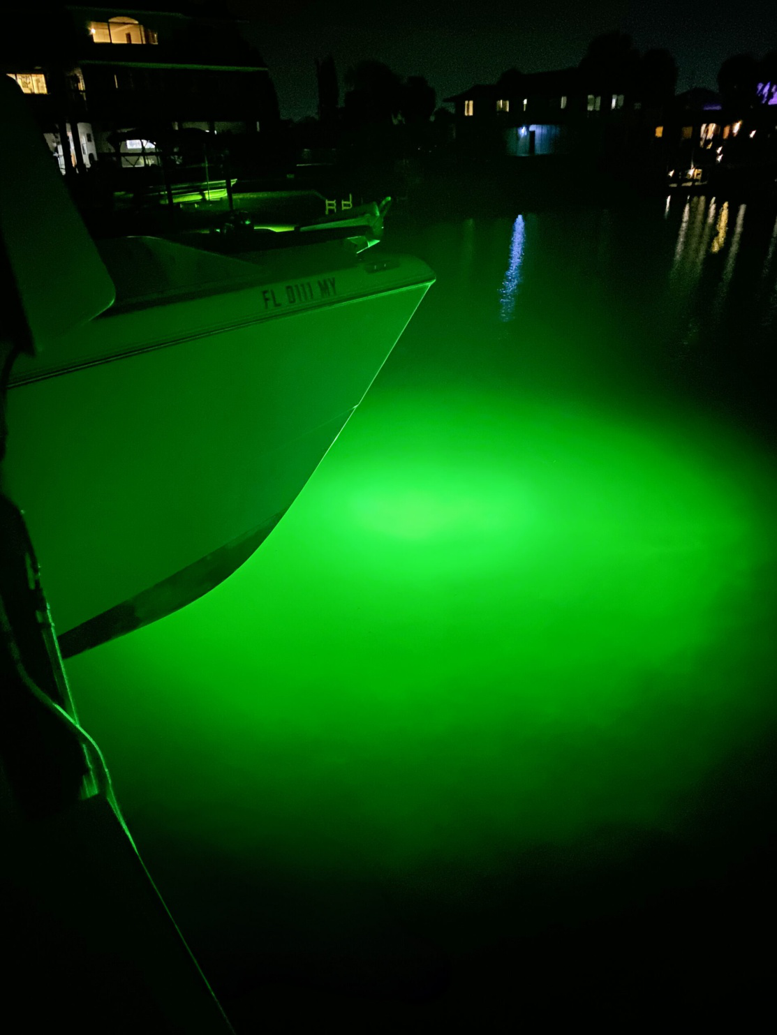 A boat illuminated by green underwater lights