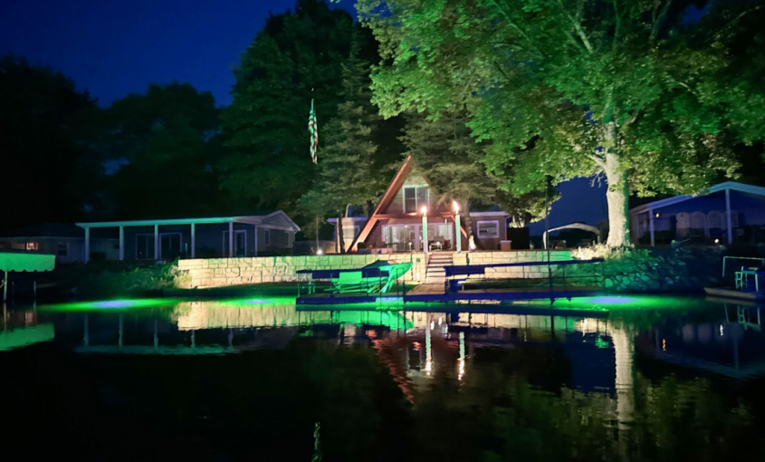 shoreline dock illuminated with green underwater lighting at night