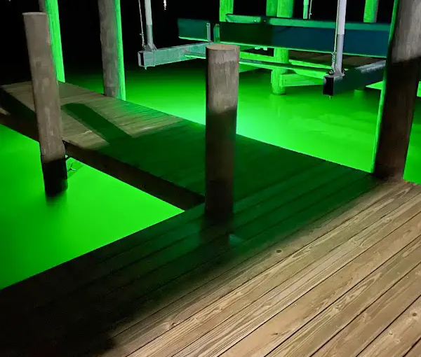 Green light illuminated in the water under the docks