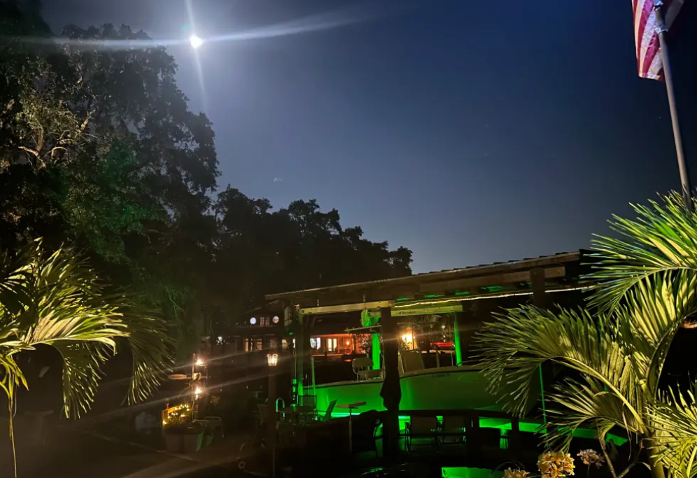 A green colored dock lights next to a property.