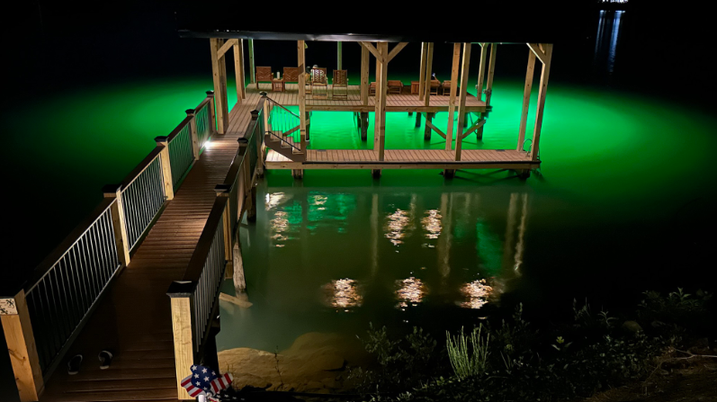  A green colored underwater LED light right beneath a dock area. 